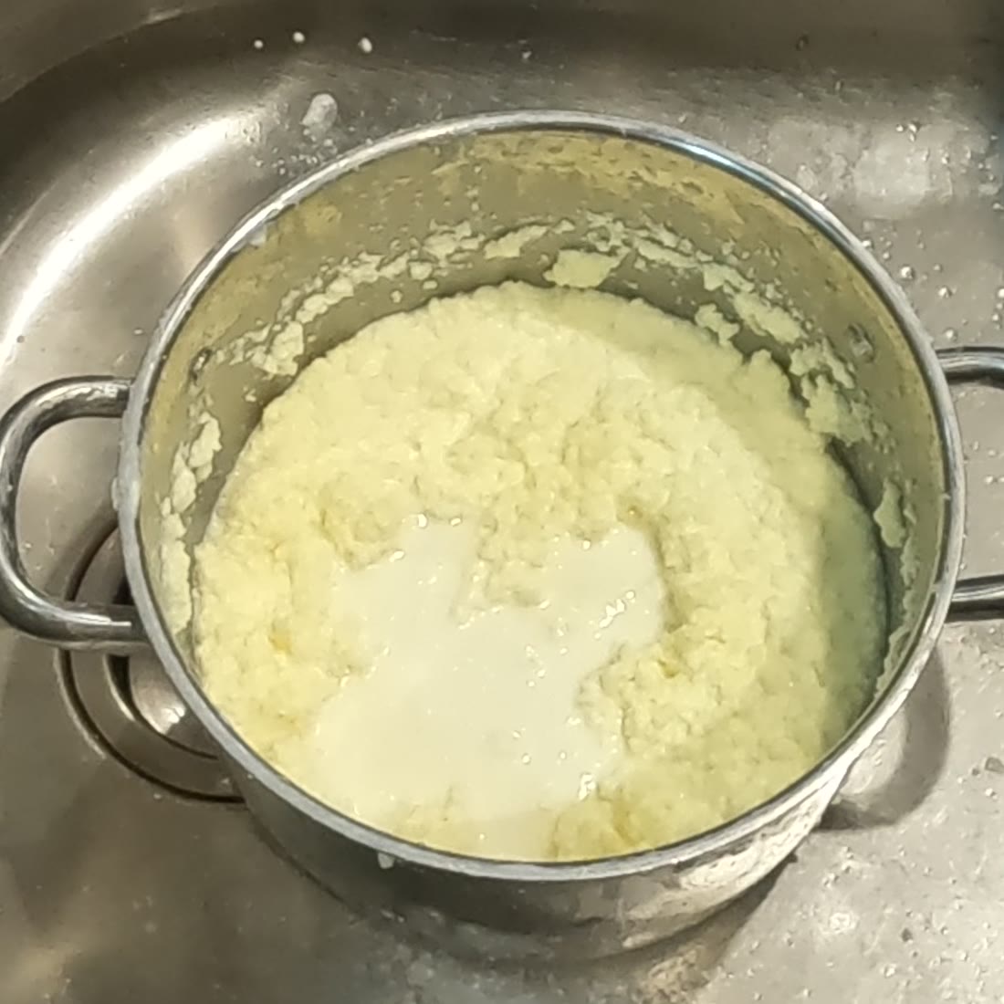 A pot of broken butter, pale yellow curds floating in cloudy buttermilk.
