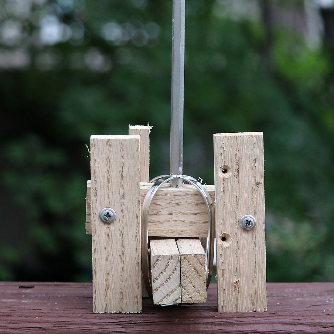 The wooden churn head standing on a rail outdoors, four hardwood arms screwed to a steel shaft and held by a metal band.