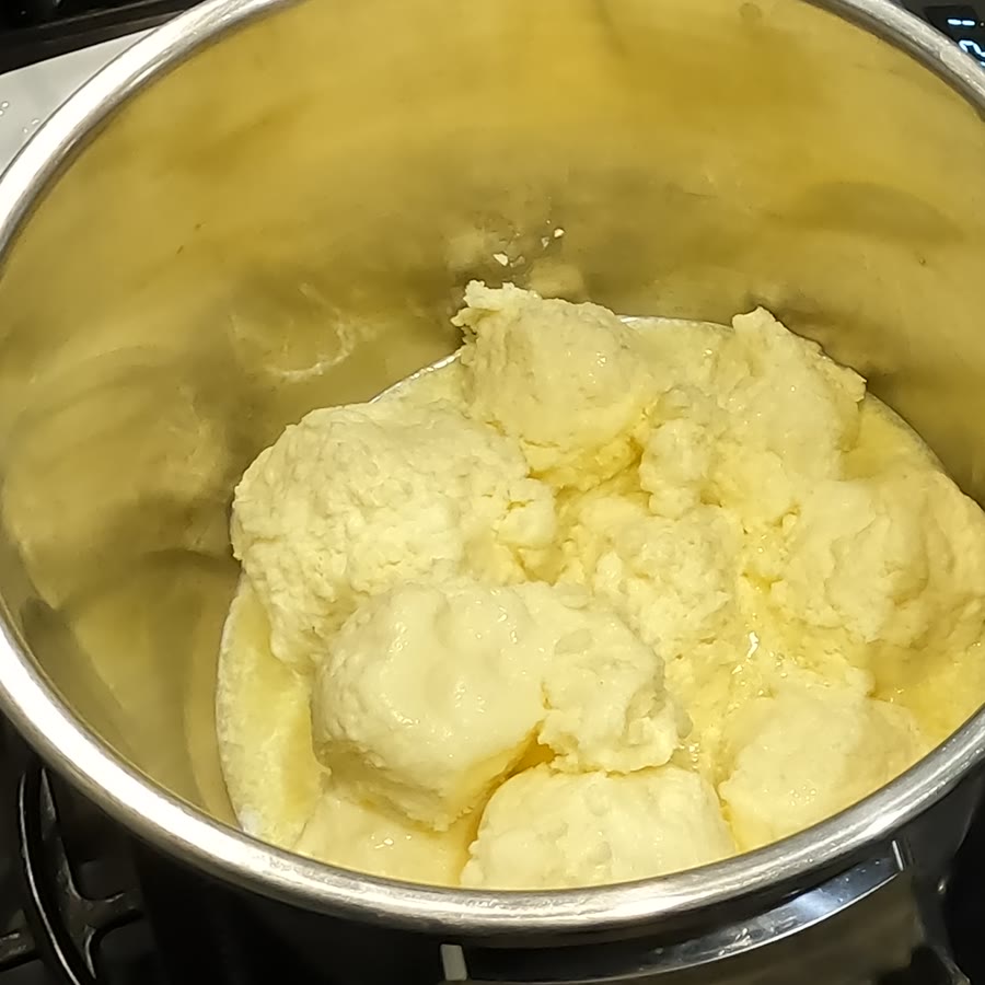 A mound of pale washed butter sitting in a steel pot before any heat.