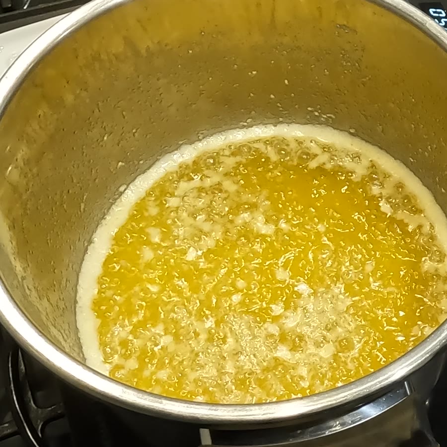 The liquid turning golden and translucent with small solids suspended in it.