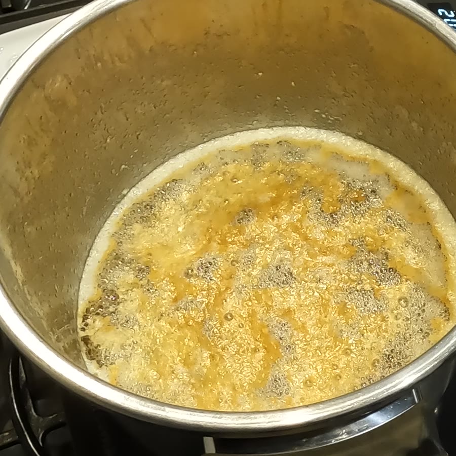 Deep golden fat bubbling with darkening milk solids across the surface.
