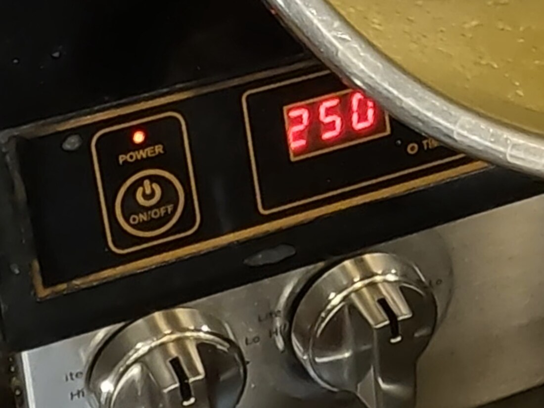 The hotplate control panel with a red digital readout showing 250, and the rim of the ghee pot above it.
